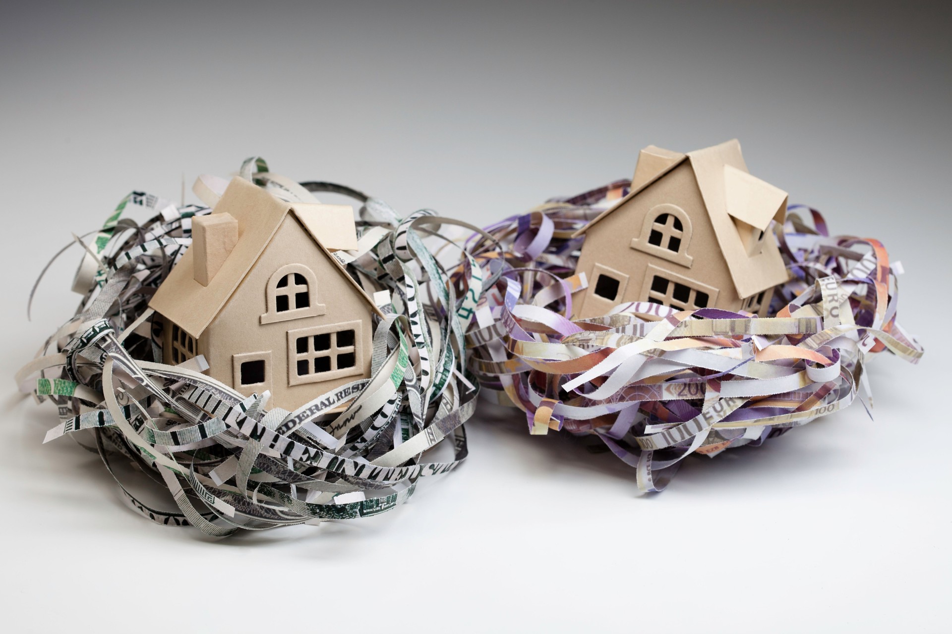 Shredded world currencies wrapped around small houses